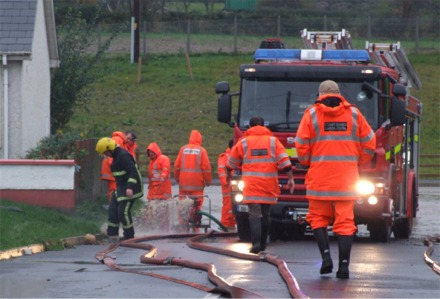 Local firemen and Coast Guard officers pump away the flood water at St Paul's Park in Greencastle.